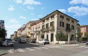 Eine Straße mit mehrstöckigen Gebäuden, parkenden Autos und einer Fußgängerampel.
