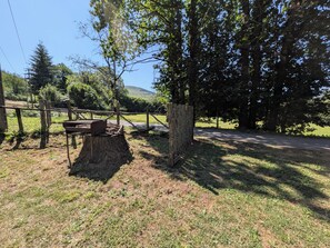 A picnic table under a large tree with a fence in the background.