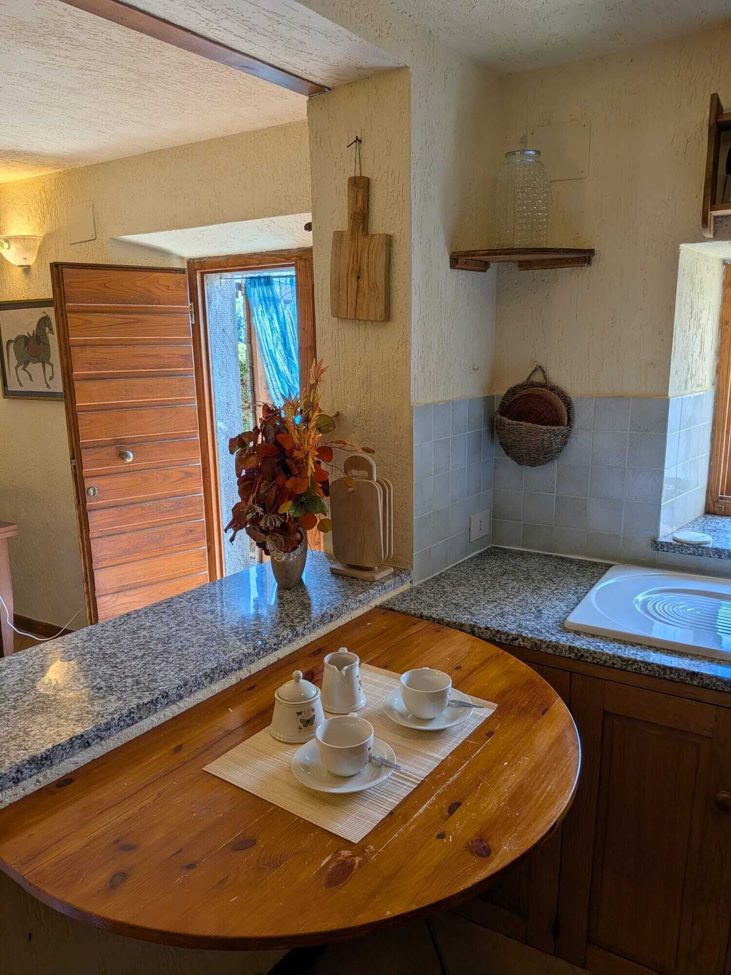 A kitchen with a wooden island, a vase with flowers, and a breakfast setup.