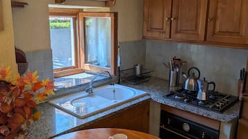 Una cucina con mobili in legno, un piano di lavoro in granito, un lavello, un fornello e una finestra con vista.