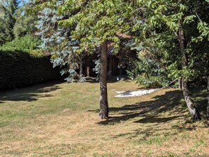 Un espace verdoyant avec un hamac, des arbres et un bâtiment en arrière-plan.