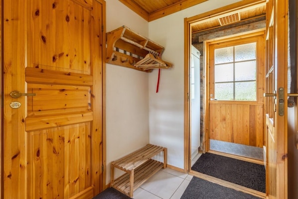 A wooden interior with a bench, a door, and a window.
