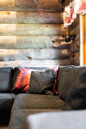 A log cabin interior with a sofa and a wall-mounted light fixture.