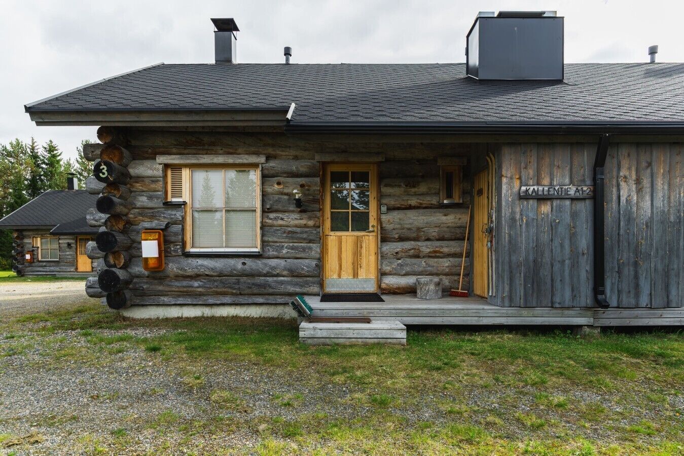 Hirsimökki, jossa on puuovi, ikkunaluukut ja savupiippu.