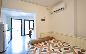 A room with a bed, a refrigerator, an air conditioning unit, and a view of an open door leading to another room. - Cozy apartment in Chioggia with WiFi (Chioggia)