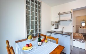A compact kitchen with a dining area, featuring a window, a sink, and a small refrigerator. - Cozy apartment in Chioggia with WiFi (Chioggia)