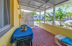 A covered outdoor area with a table set for dining, a bench, and a view of the surrounding area. - Cozy apartment in Rosolina with WiFi (Rosolina)