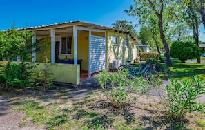 Ein gelbes Haus mit überdachter Veranda, einem Fahrrad und einem kleinen Garten.