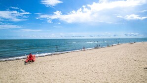 Ein Strand mit blauem Himmel, ruhiger See und einigen Personen.