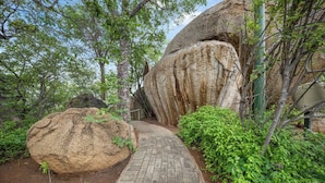 A paved pathway leading through a natural setting with large rocks and dense greenery. - Boulders Bush Lodge: A Private Boulder-Top Retreat in Greater Kruger (Mica)