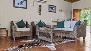A living room with patterned furniture, a zebra rug, and wall art. - Boulders Bush Lodge: A Private Boulder-Top Retreat in Greater Kruger (Mica)