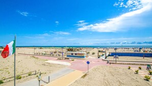 Blick auf einen Strand mit einer Flagge, einem Gebäude mit Beschilderung und blauem Himmel.