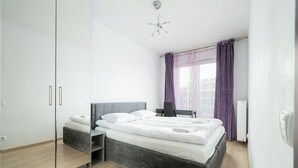 A modern bedroom with a bed, a chair, a desk, and a wardrobe. - RentPlanet - Apartament Obozowa (Warszawa)