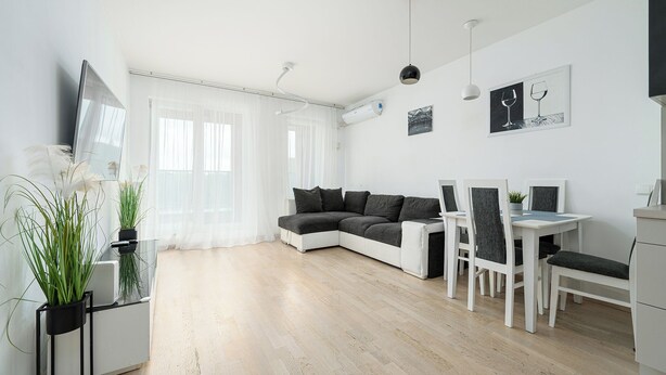 A modern living room with a sofa, dining table, chairs, and a TV. - RentPlanet - Apartament Obozowa (Warszawa)