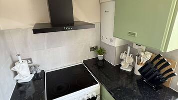 Une cuisine moderne avec un fourneau noir, des armoires blanches et un mur vert.