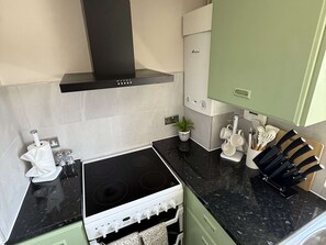 A modern kitchen with a black stove, white cabinets, and a green wall.