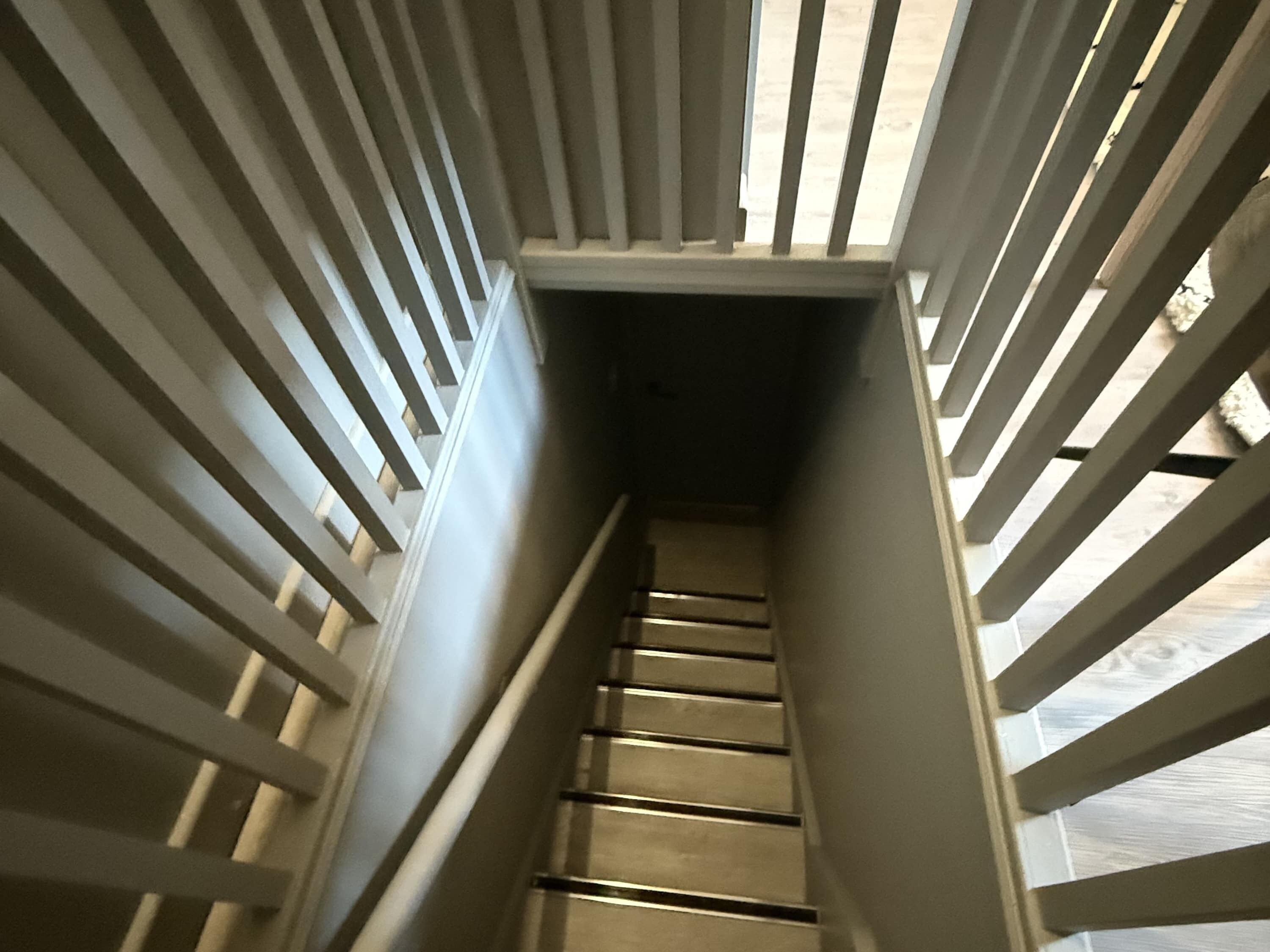 Un escalier étroit avec des rampes en métal et un plancher en bois.