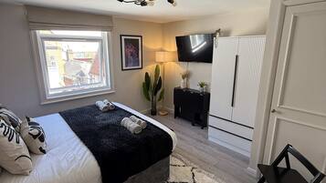 Une chambre à coucher avec un lit, une télévision, une armoire, un bureau et une fenêtre.