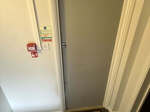 A door with a fire action panel, a lock, and a small emergency exit sign.