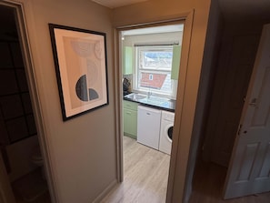 Un pasillo que conduce a una cocina con ventana, lavavajillas y lavadora.