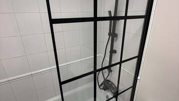 Une cabine de douche dotée d’une porte en verre et d’un cadre noir.