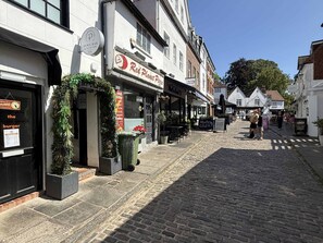 Una calle adoquinada bordeada de comercios, entre ellos una Red Planet Pizza y un Pews Bar & Courtyard.