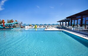 A swimming pool with a slide and lounge chairs, a covered area with umbrellas, and a view of the ocean. - Amazing home in Torino di Sangro with swimming pool (Torino di Sangro)