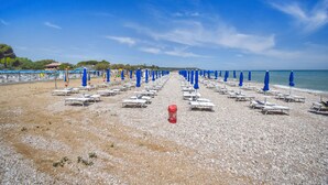 A beach with rows of sun loungers and blue umbrellas, a red cooler, and a clear sky. - Awesome home in Torino di Sangro with WiFi (Torino di Sangro)