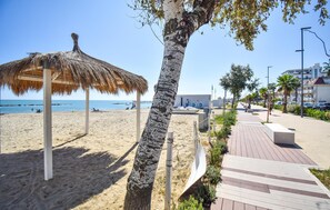 A beach with a thatched structure, a palm tree, and a paved walkway. - Awesome apartment in Martinsicuro with WiFi (Martinsicuro)