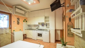 A compact kitchen with a stove, sink, and cabinets, a bed, and a television mounted on the wall. - Awesome apartment in Martinsicuro with WiFi (Martinsicuro)