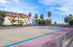 An empty sports court with a blue and pink boundary, surrounded by a metal railing. - Awesome apartment in Martinsicuro with WiFi (Martinsicuro)