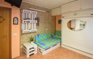 A compact living space with a sofa, a small table, a potted plant, and a white cabinet with a circular mirror. - Awesome apartment in Martinsicuro with WiFi (Martinsicuro)