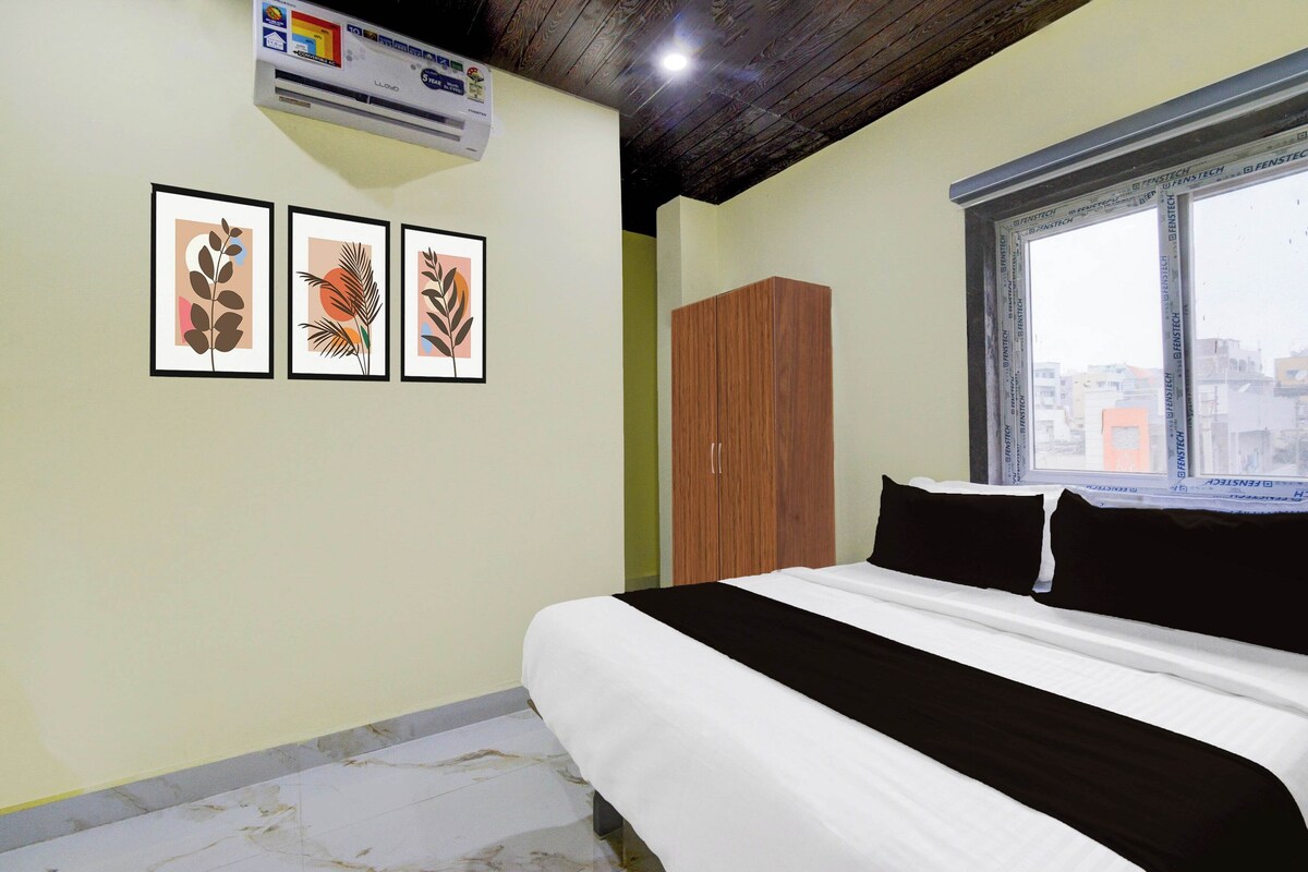 A bedroom with a bed, a wardrobe, and three framed artworks on the wall.