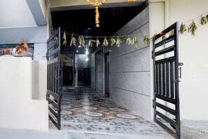 A hallway with patterned floor tiles, a metal gate, and hanging dried leaves. - Collection O Srisailam Highway (Hyderabad)