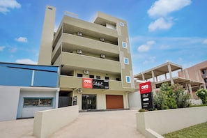 A multi-story hotel with a modern design, featuring balconies and air conditioning units. - Collection O Srisailam Highway (Hyderabad)