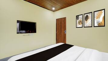 Habitación de hotel con cama, televisor montado en la pared y tres obras de arte enmarcadas.