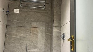 A bathroom with a shower, toilet, and a towel rack. - Hotel Skyboat Inn (Nashik)