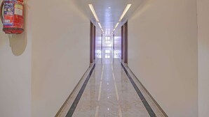 A hallway with a fire extinguisher mounted on the wall, recessed lighting, and a reflective marble floor. - Hotel Skyboat Inn (Nashik)