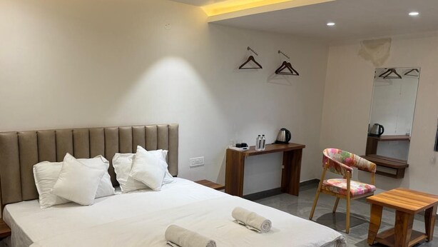 A hotel room with a large bed, a desk, a chair, and a mirror. - Hotel Skyboat Inn (Nashik)