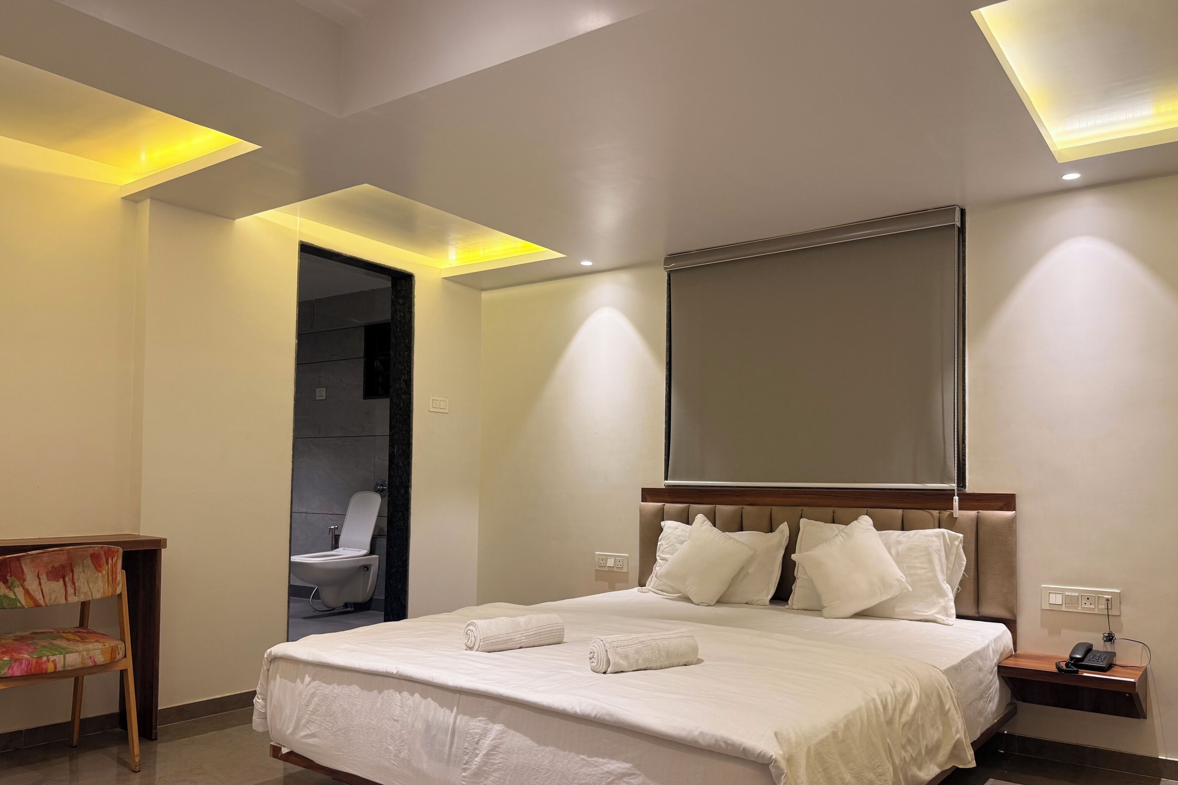 Una habitación de hotel con una cama grande, una mesita de noche con un teléfono y un espejo sobre la cama.