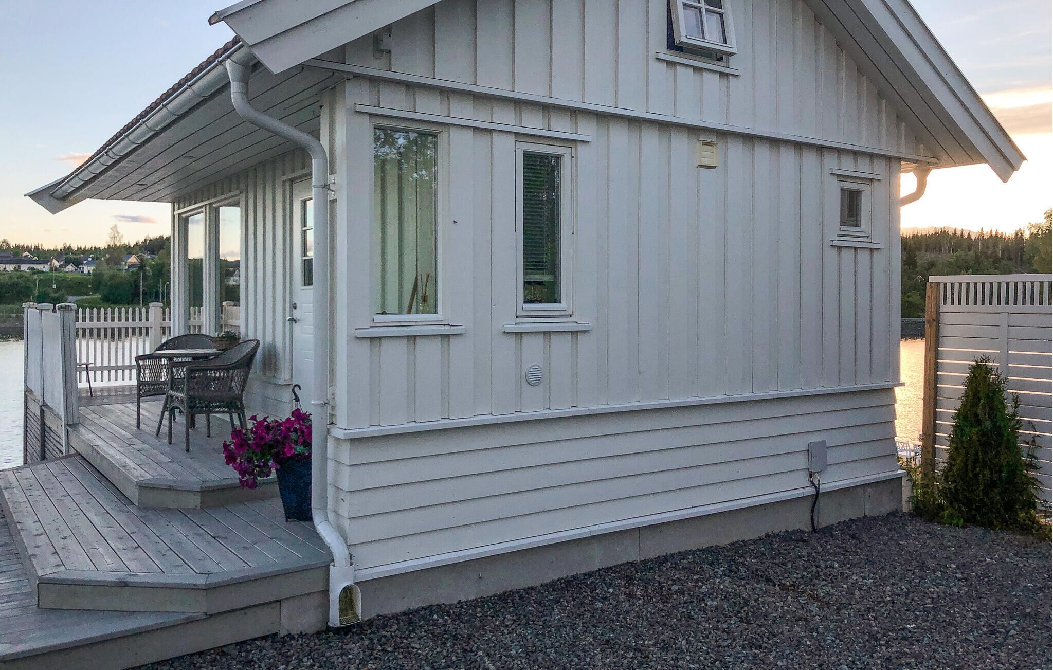A white building with a covered porch, a small table, and chairs.