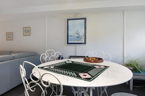 Un comedor con una mesa redonda, sillas blancas y un tapete para mesa de póker.