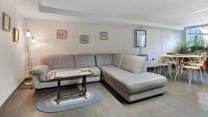 Una sala moderna con un sofá seccional, una mesa de centro y un comedor con sillas y una mesa.