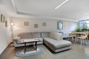 Una sala moderna con un sofá seccional, una mesa de centro y un comedor con sillas y una mesa.