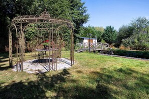 A gazebo with a circular base and intricate metalwork, surrounded by a grassy area and trees. - Bed and Breakfast 'La Prairie De Vassy 14 - Chausey' with Shared Terrace, Wi-Fi and Air Conditioning (Valdallière)