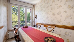 Un comedor con una mesa preparada para dos personas, una ventana con vistas a árboles, y un radiador en la pared.