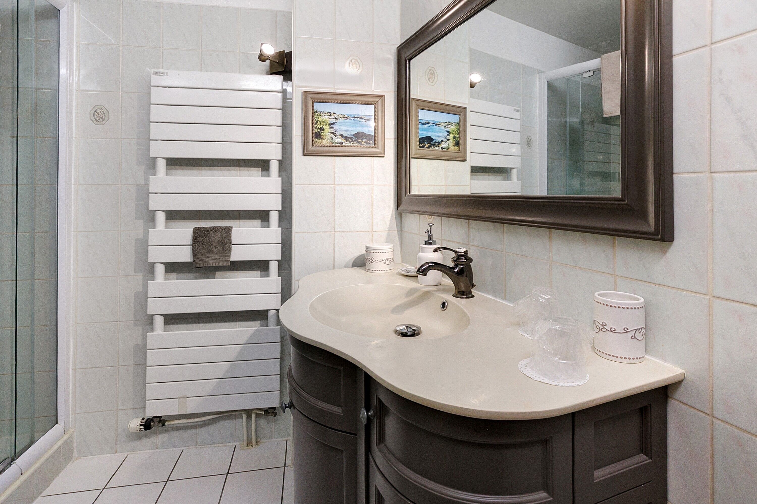 Une salle de bain avec une baignoire blanche, un lavabo avec un miroir au-dessus et un porte-serviettes.