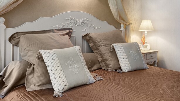 Un dormitorio con cama, almohadas, una mesita de noche con lámpara y dosel.