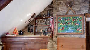 Una zona de bar con taburetes, una estantería con trofeos y un cuadro en la pared.