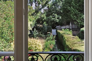 Un jardin avec un sentier, des arbres et une clôture blanche.